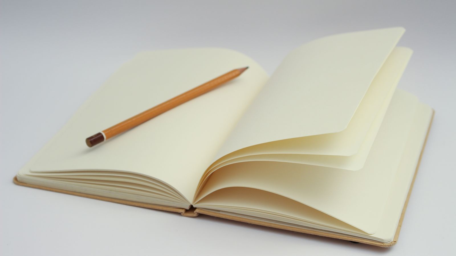 An open notebook with blank pages and a yellow pencil