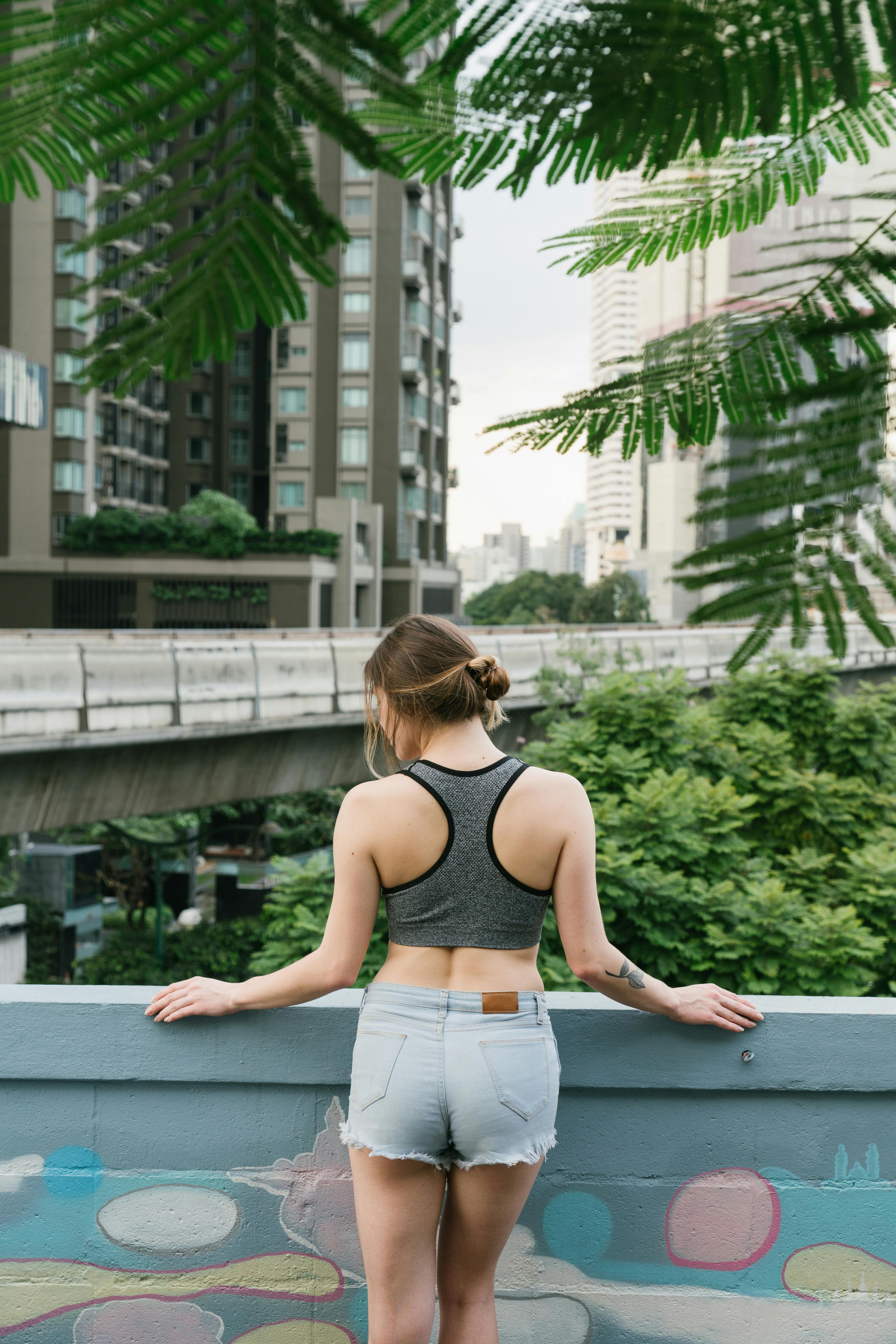 Foto de stock gratuita sobre chaqueta con capucha, de espaldas, mochila,  montañas, mujer, pantalones cortos, puesta de sol, shorts, Signo de la paz,  sol, tiro vertical