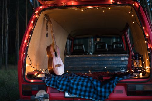 Free A serene camping scene with an acoustic guitar and lights in a car trunk, perfect for music lovers. Stock Photo