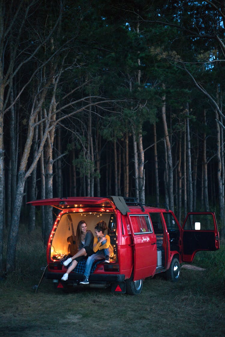 Woman Sitting On Car Back On Camping And Talking