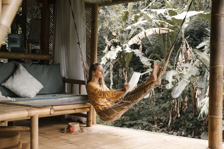 A Woman Sitting On A Hammock While Holding A Sketchbook