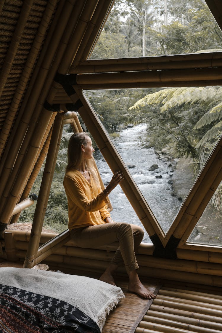 A Woman Sitting By The Window While Looking At The View