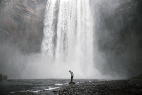 A Person Standing Near the Cascading Waterfalls