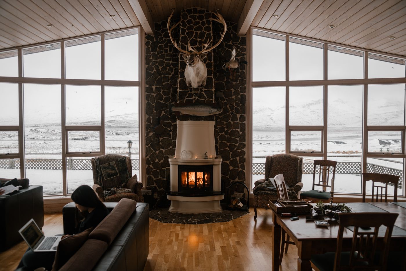 A cozy living room with a lit fireplace, soft seating, and warm lighting
