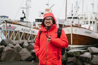 Man in Red Hoodie Standing on Rocky Shore
