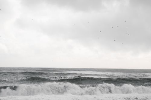 Free Powerful ocean waves crash beneath a cloudy sky, offering a serene yet dramatic seascape. Stock Photo