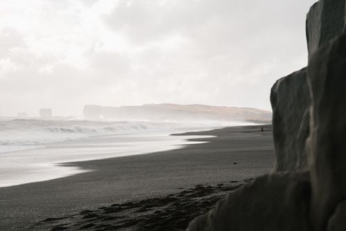Free Captivating coastal view featuring black sand beaches and rugged cliffs under overcast skies. Stock Photo