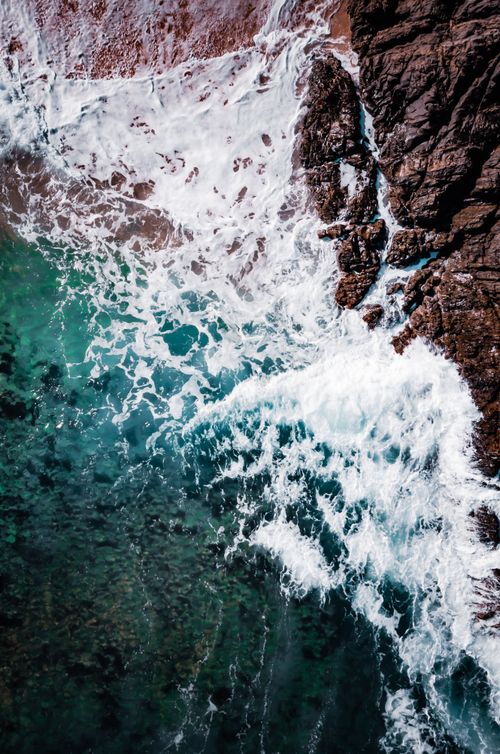 Free Dramatic aerial view of ocean waves crashing against rocky coastline in Calabarzon, Philippines. Stock Photo