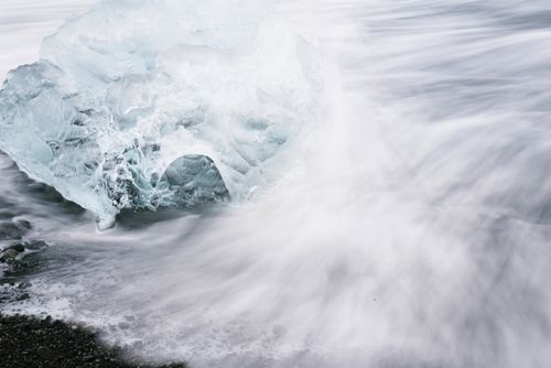 Free A dramatic ice block meets ocean waves on a rocky coast, showcasing nature's power. Stock Photo