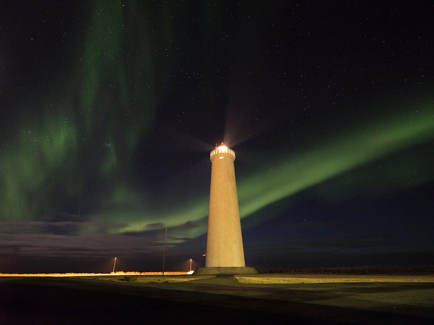 Illuminated lighthouse with stunning aurora borealis in the night sky.
