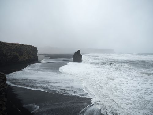 Free Moody scene of fog-covered cliffs and rocky shoreline by the sea on an overcast day. Stock Photo
