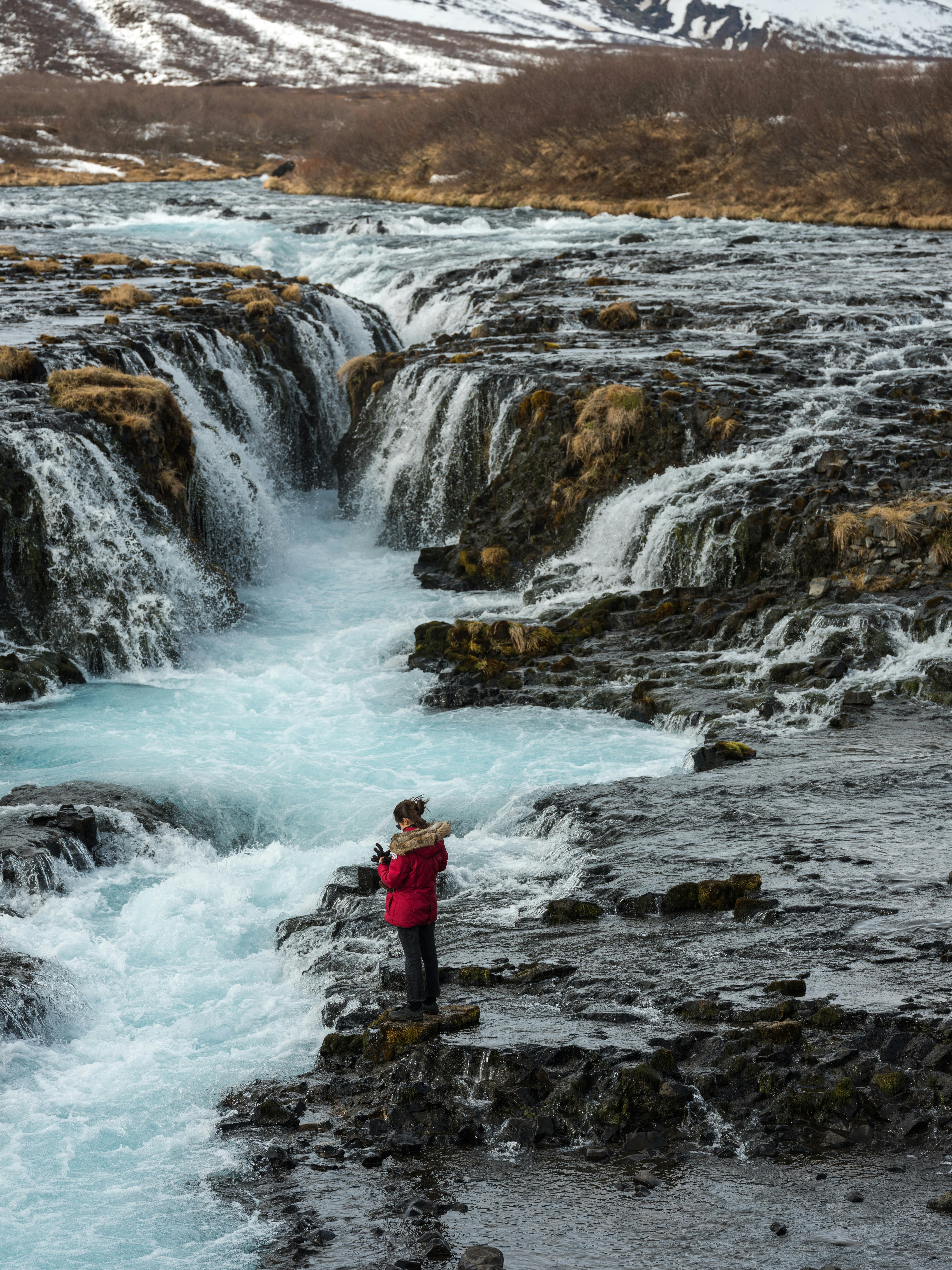 一个女人站在瀑布旁的岩石景观中，拥抱大自然的美丽