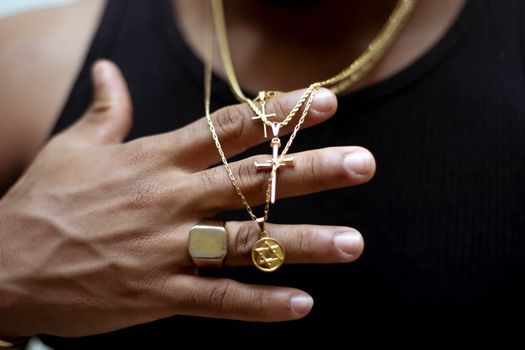 Unrecognizable crop ethnic male in golden chains with crosses and six pointed star of David