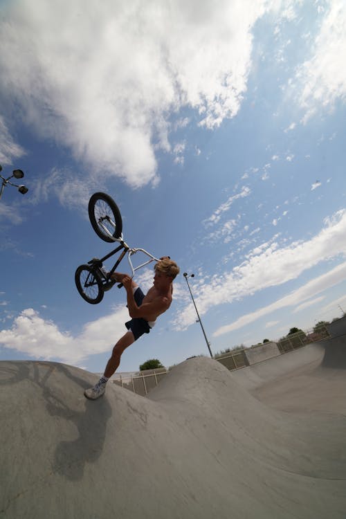 Free From below full body of shirtless male rider doing dangerous tricks on ramp with bike Stock Photo