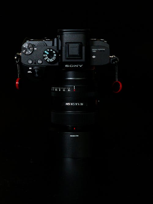 From above of modern digital photo camera with professional zoom lenses against black background