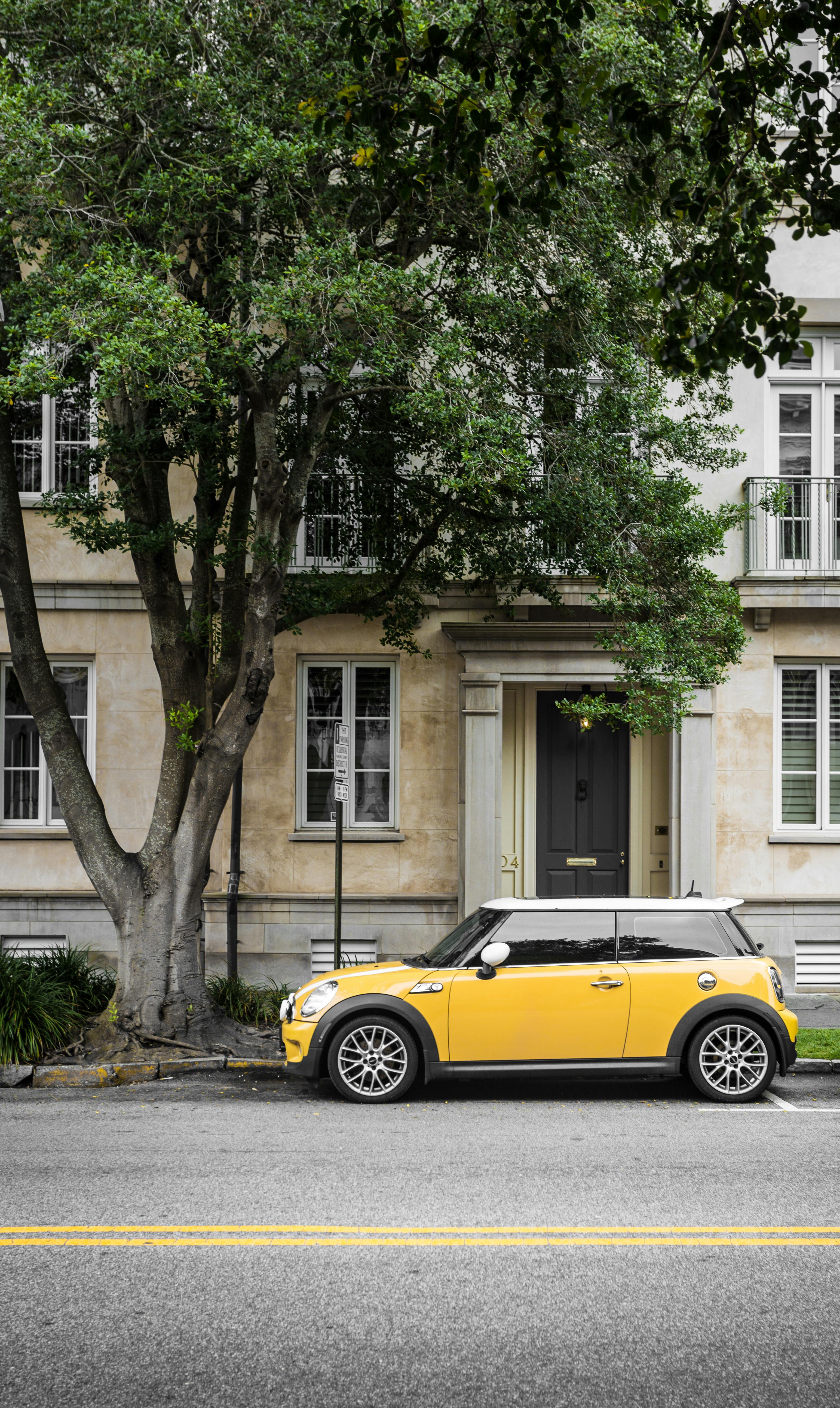 yellow mini cooper parked beside white concrete building