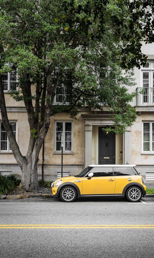 желтый Mini Cooper припаркован у белого бетонного здания