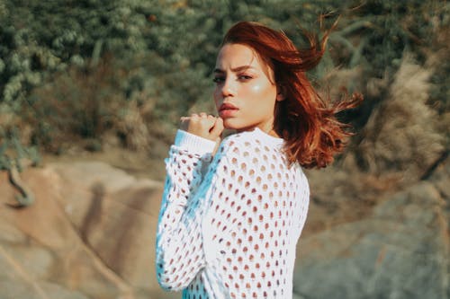 Thoughtful young female tourist resting in nature on windy day