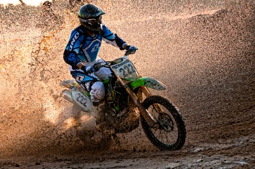 Free Motocross rider racing through mud with dramatic water spray in Kuwait. Stock Photo