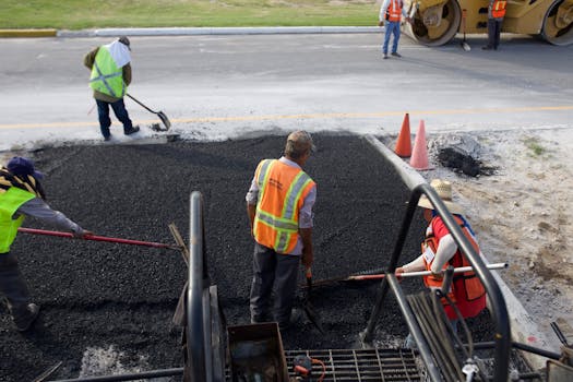 Group of road construction workers laying fresh asphalt outdoors during the day.