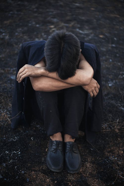 Free Unrecognizable depressed man embracing knees on ground Stock Photo