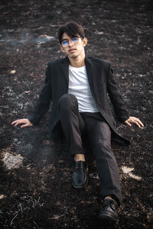 Elegant young Asian man sitting on burnt grass
