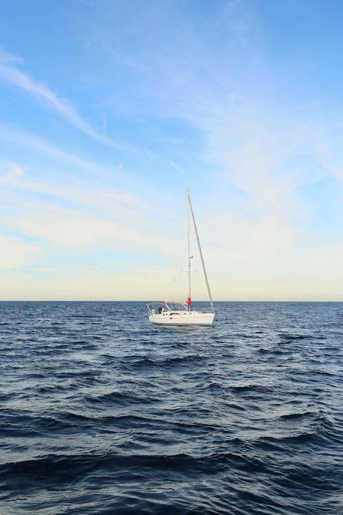 Free Modern sailboat floating on picturesque endless waving sea against bright cloudy blue sky Stock Photo