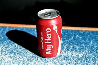 From above of red metal can with refreshing fizzing coke placed on table in cafe