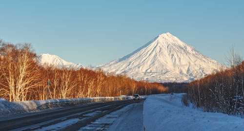 Car driving on snowy highway in sunny day