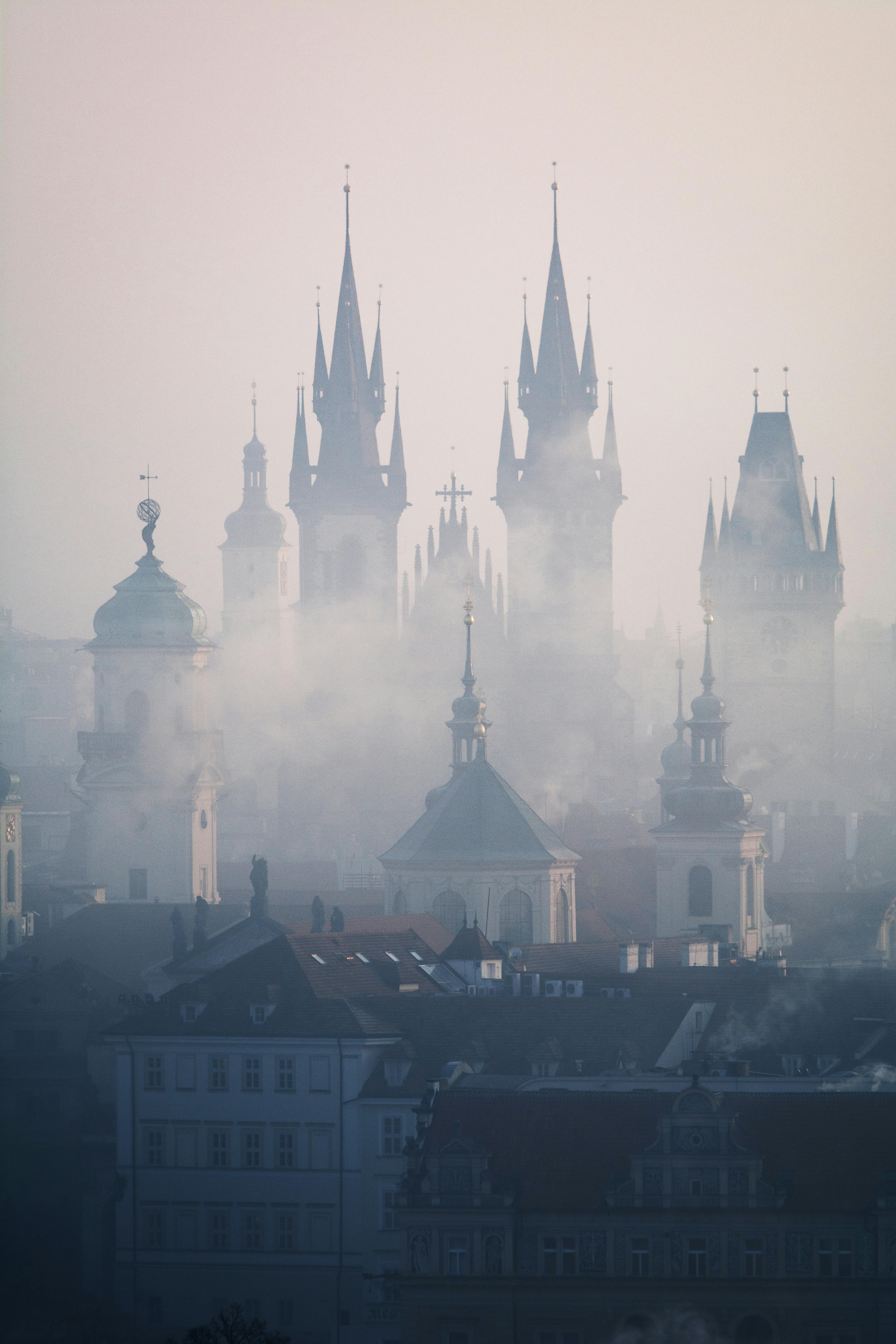 Misty morning view of Prague's iconic gothic spires rising through the fog, creating a mysterious atmosphere.