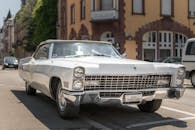 一辆白色古董车停在阳光明媚的街道上，车身上贴着“新婚”的标志