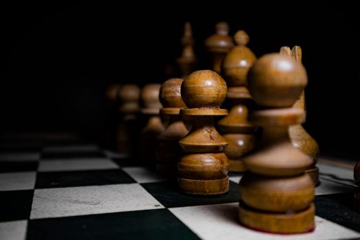 Close-up of wooden chess pieces on board, emphasizing strategy and focus.