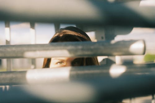 Young woman looking at camera through metal railing