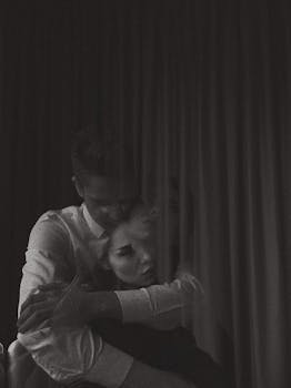 Moody black and white portrait of a couple embracing, creating an emotional and intimate atmosphere.