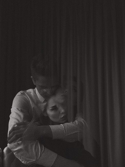Moody black and white portrait of a couple embracing, creating an emotional and intimate atmosphere.