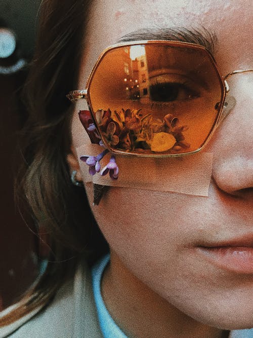 Crop young female wearing trendy sunglasses with small blooming flowers under patch on wound