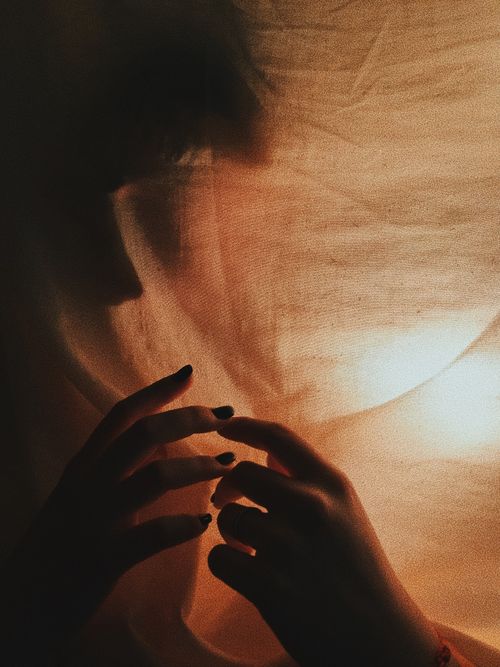 Free Unrecognizable female in dark room with lamp wrapped in white cloth at night Stock Photo