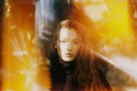 一位年轻迷人的长发女性，在明亮的黄色灯光下看着相机