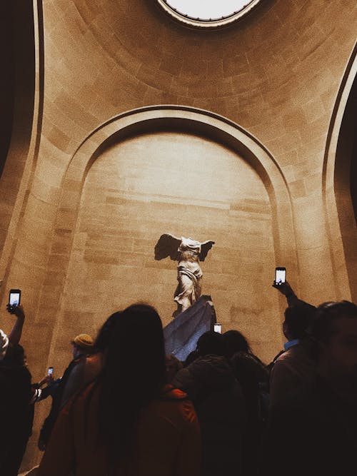 Tourists taking photo of ancient sculpture in museum