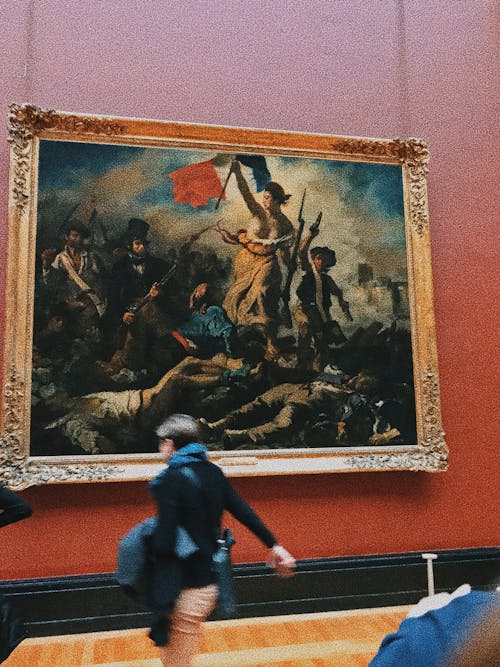Free Tourist in museum with famous painting Liberty Leading People showing woman leading varied group of people forward barricade Stock Photo
