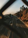 From above of contemporary cars driving on smooth surface of roadway near hills and houses