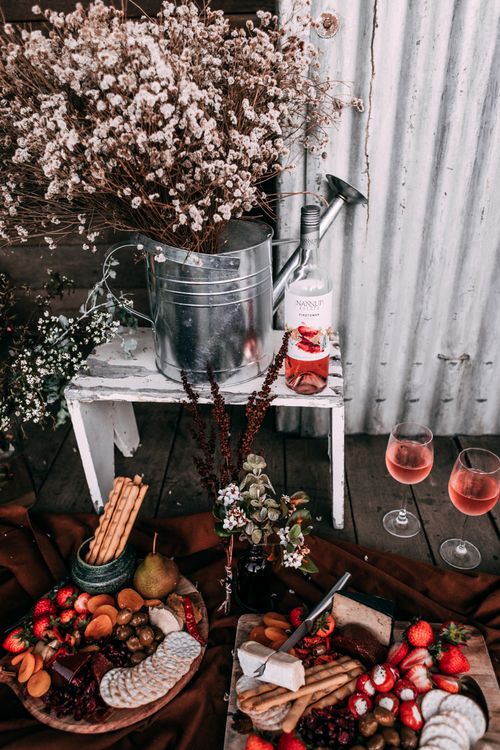 Free Charming picnic setup with wine, cheese, and flowers in a rustic outdoor setting. Stock Photo