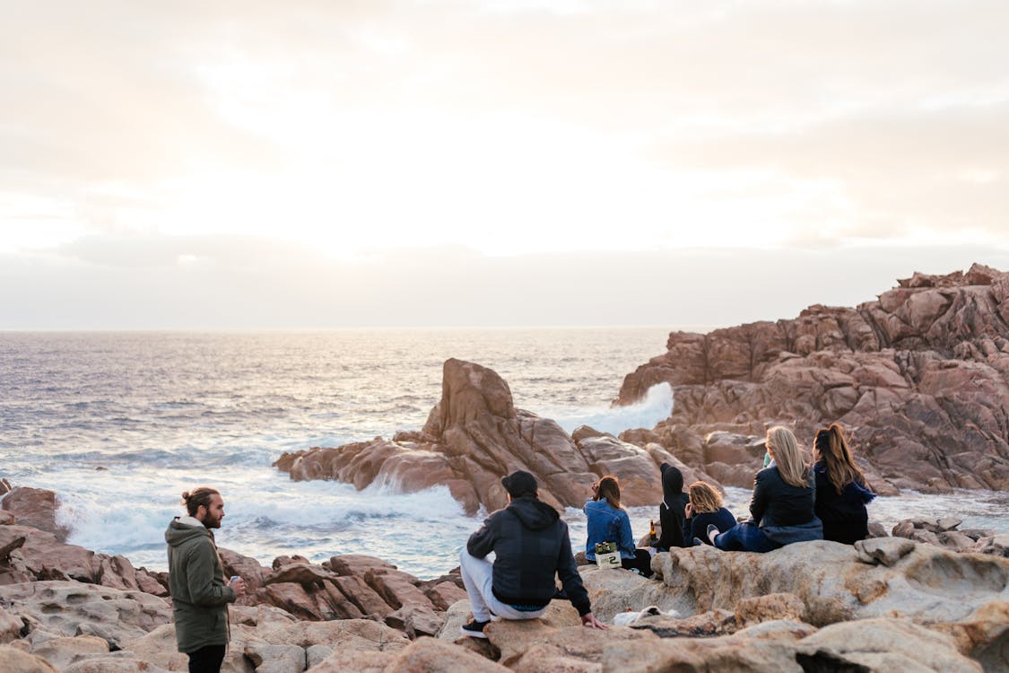 Free Group of friends resting on rocky coast Stock Photo