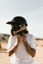 一名身穿白色衬衫、头戴黑色头盔、手臂有纹身的匿名民族骑行者，背景模糊