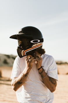 Anonymous ethnic biker with in white shirt and black helmet with tattoos on arms on blurred background