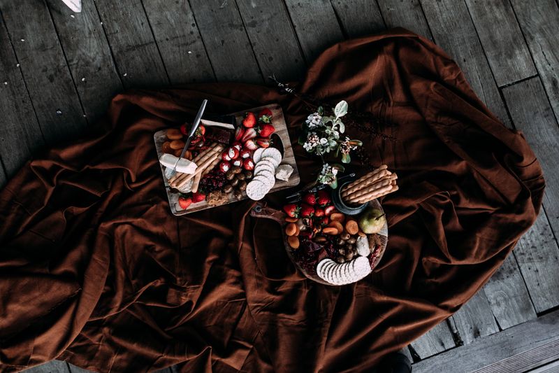 Overhead spread of fruit and crackers on a rust-brown picnic throw — photo by Rachel Claire on Pexels