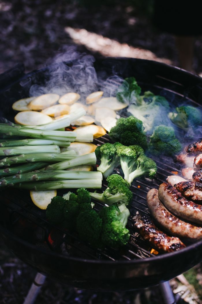 Vegetables and sausages cooking on an outdoor grill