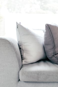 Modern gray sofa with cushions in a serene, minimalist living room setting.