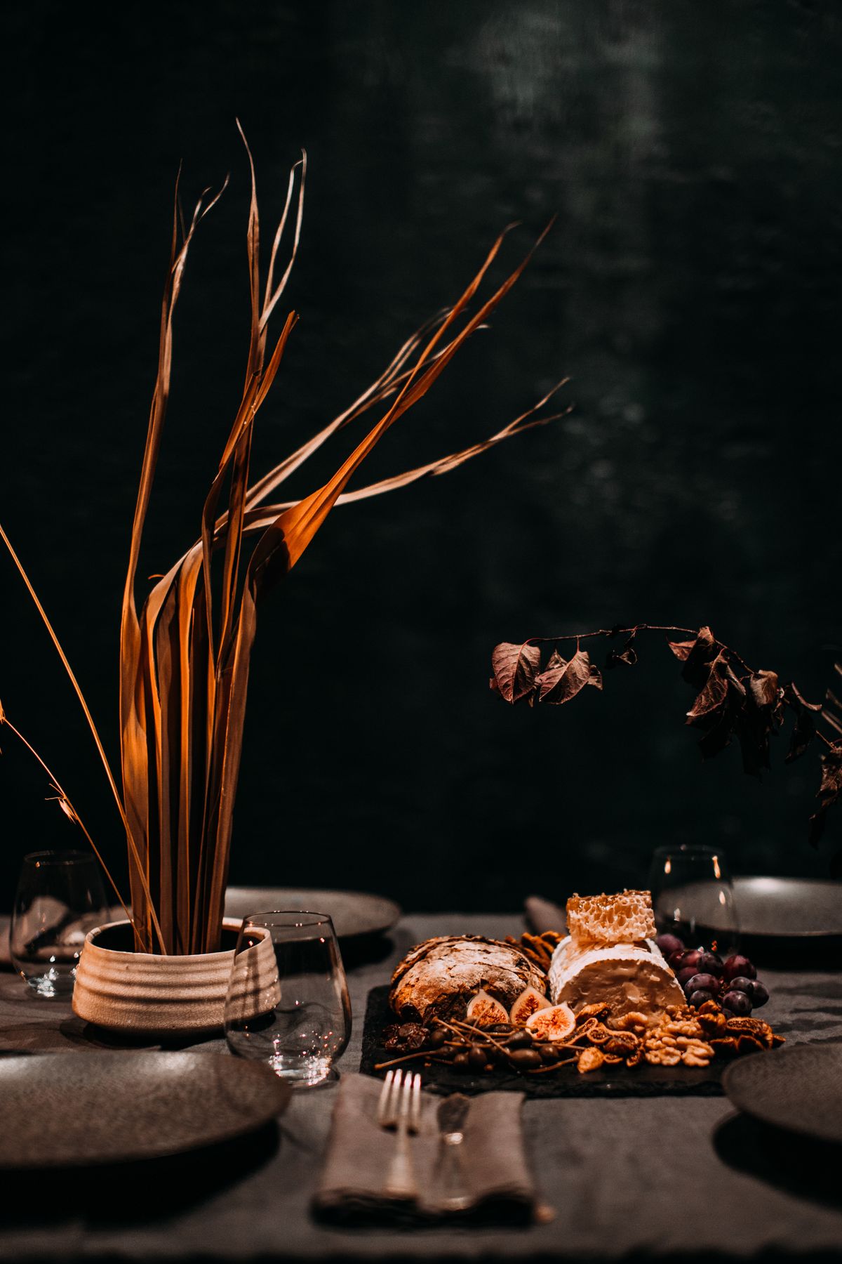 Creative decoration of banquet table with appetizing dessert near dry plant in vase and tableware in cafe with dark illumination Stock Photo.