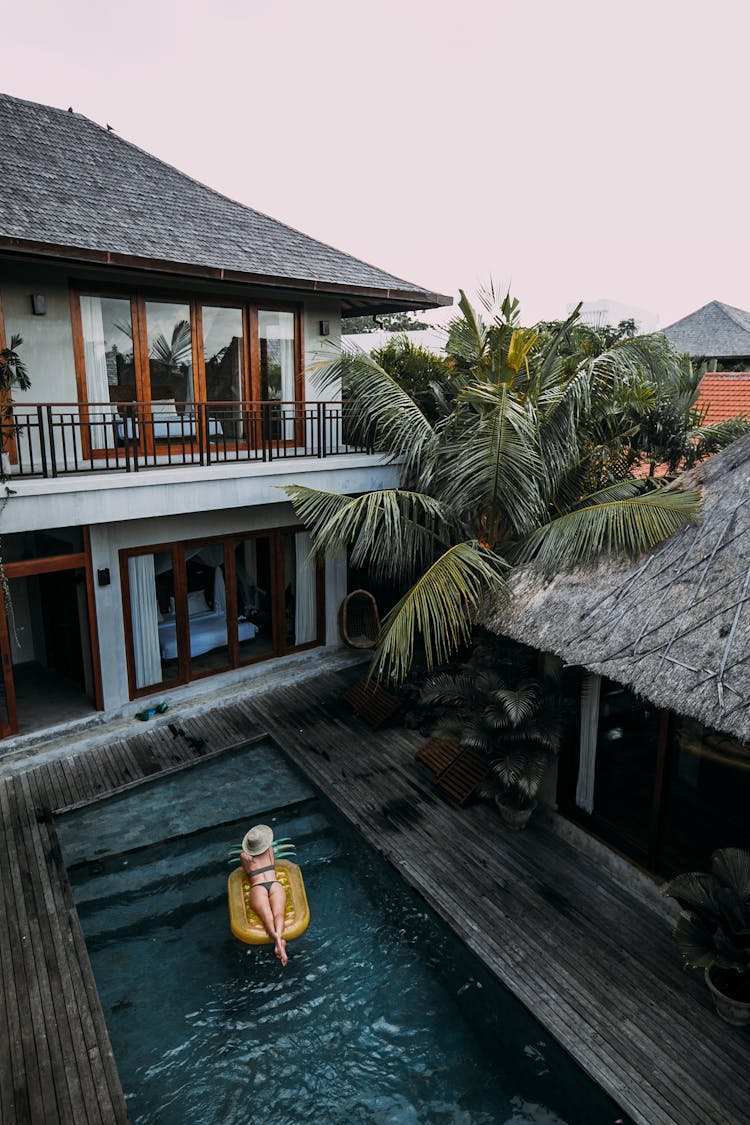 Woman Resting In Pool Near Cottage